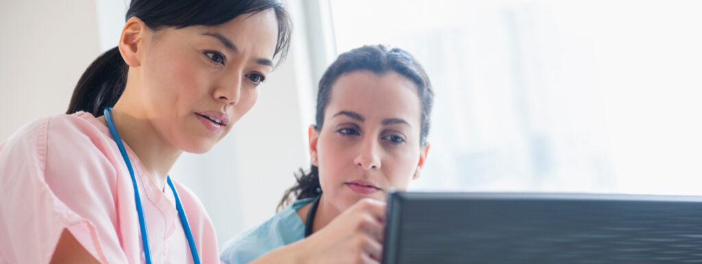 two healthcare professionals work together looking at a computer